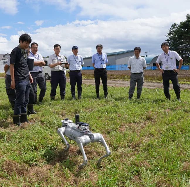 ほ場で四足歩行ロボットの実証実験を見学する参加者
